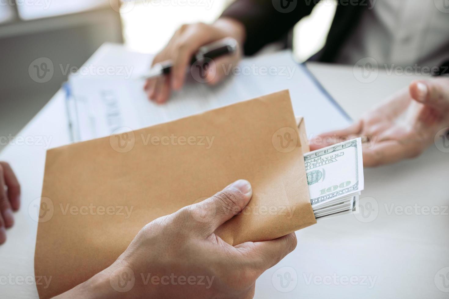 geschäftsmann, der heimlich ein bestechungsgeld gibt, indem er geldscheine im umschlagvertragsdokument gibt. foto