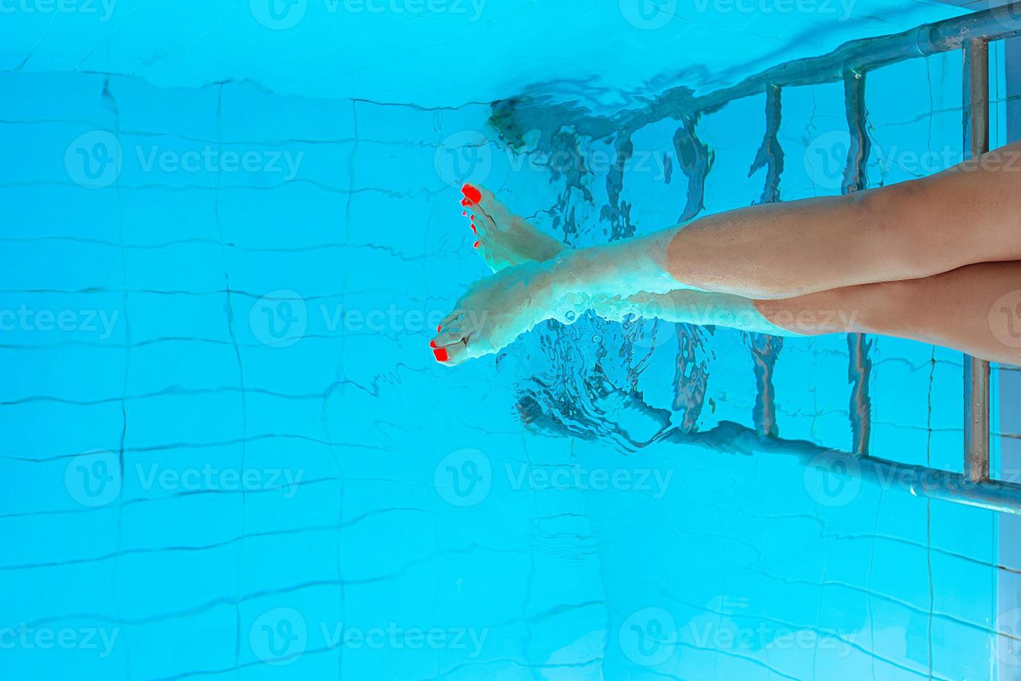 erwachsene weiße kaukasische europäische frauenbeine mit orangefarbener uv-pediküre unter wasser im schwimmbad. Sommer. lustige unterwasserbeine im schwimmbad, im urlaubs- und sportkonzept. foto