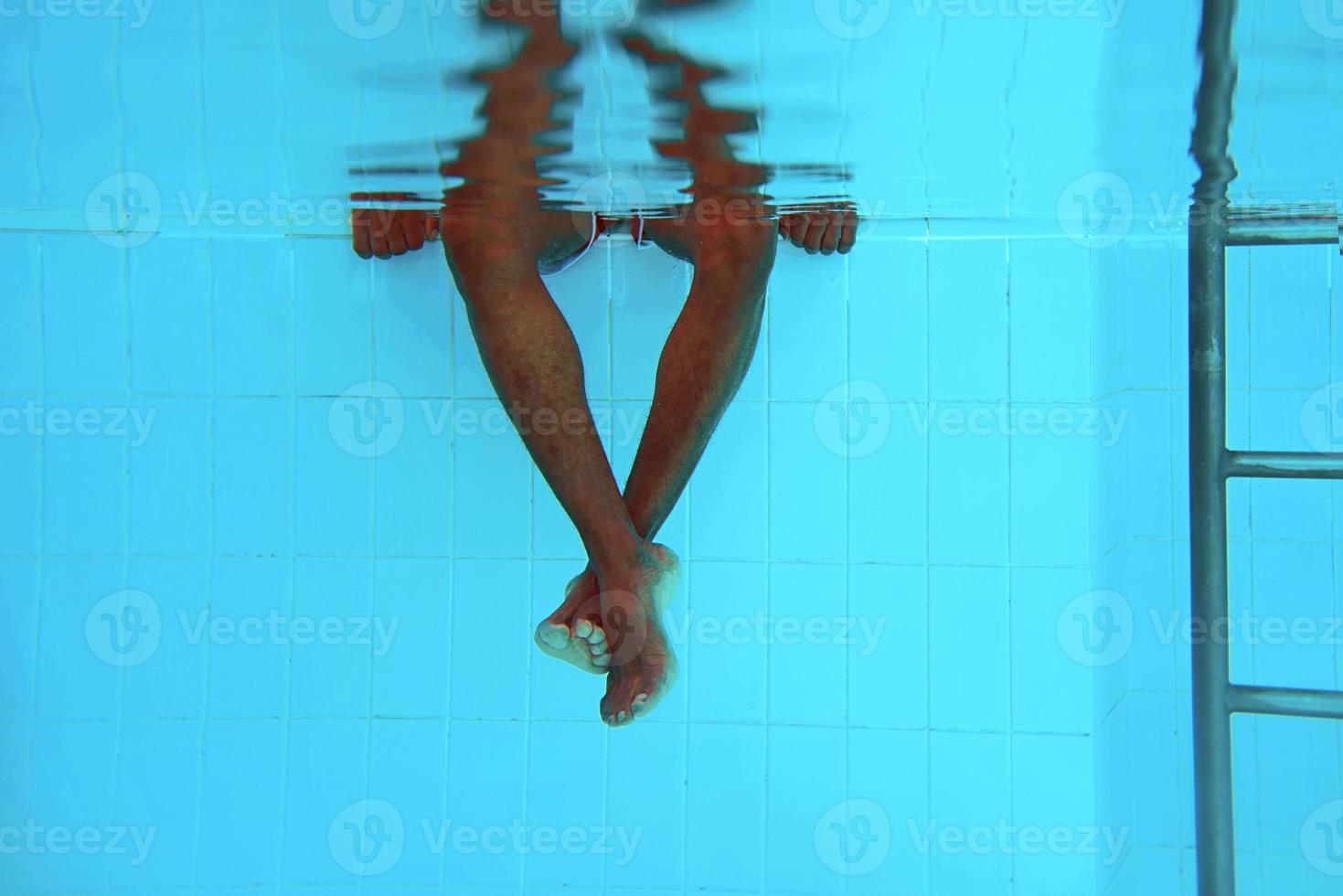 Die Beine eines erwachsenen afroamerikanischen Mannes unter Wasser im Schwimmbad foto