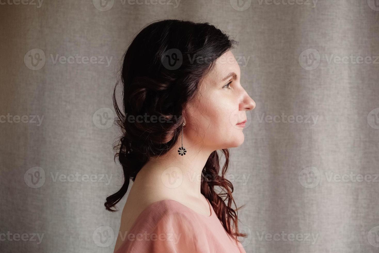 Porträt einer brünetten Frau in einem rosafarbenen Kleid auf einem Hintergrund aus Leinenstoff. kopieren, leerer platz für text foto