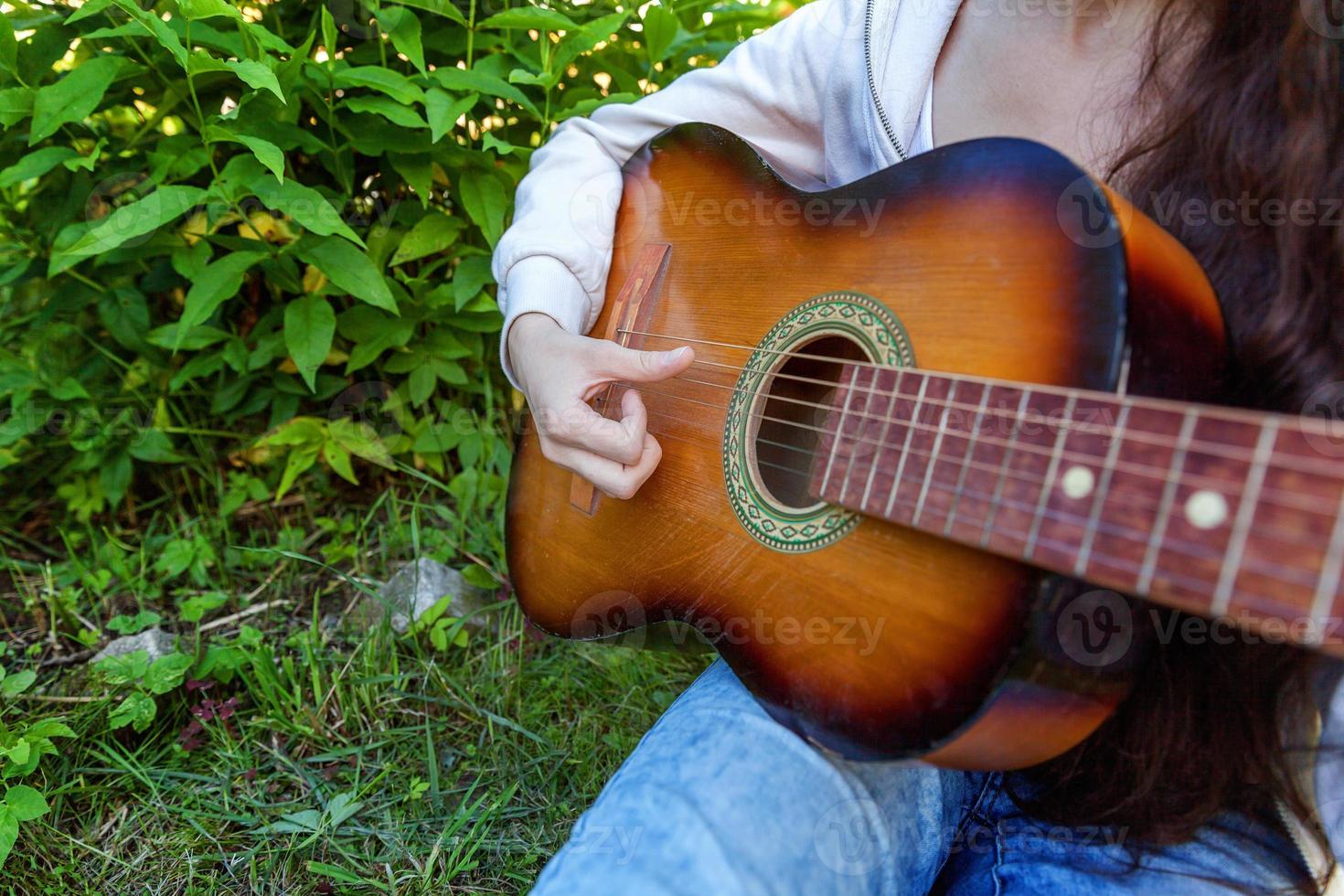 frauenhände, die akustikgitarre spielen foto