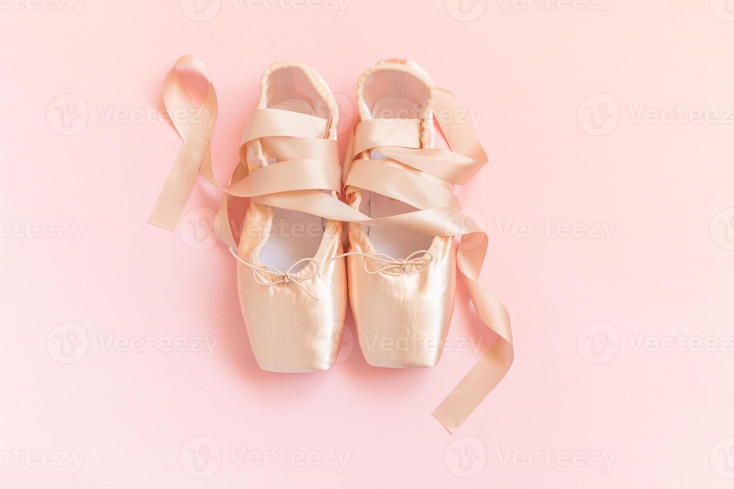 Neue pastellbeige Ballettschuhe mit Satinband isoliert auf rosa Hintergrund. Ballerina Klassische Spitzenschuhe für das Tanztraining. Ballettschulkonzept. draufsicht flach liegend, kopierraum foto
