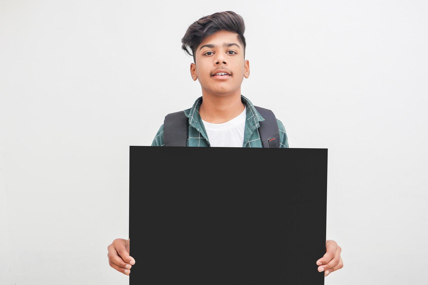 Indischer College-Student, der Brett auf weißem Hintergrund zeigt. foto