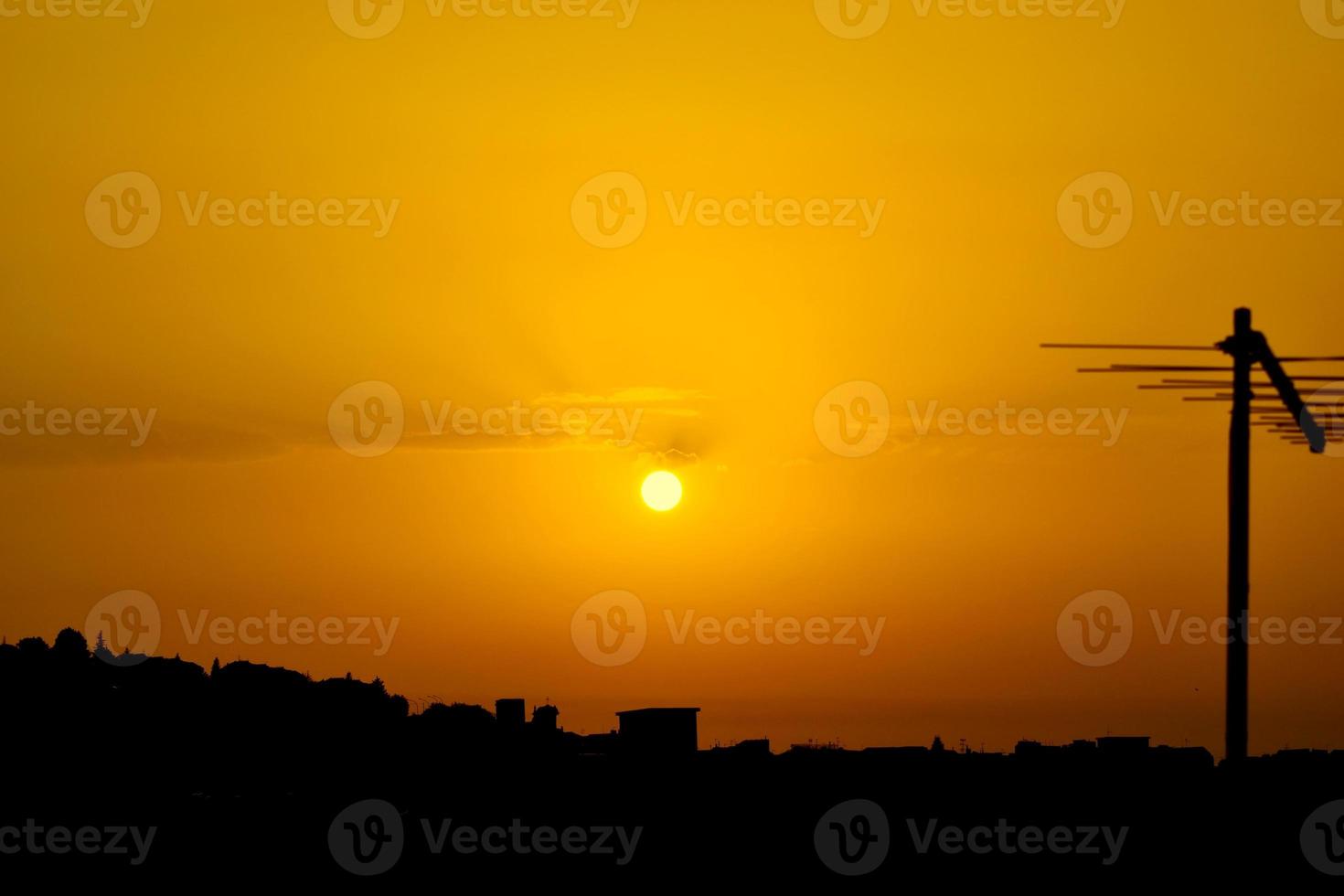 orange-gelber Sonnenuntergang mit der Silhouette einer Antenne auf der rechten Seite foto