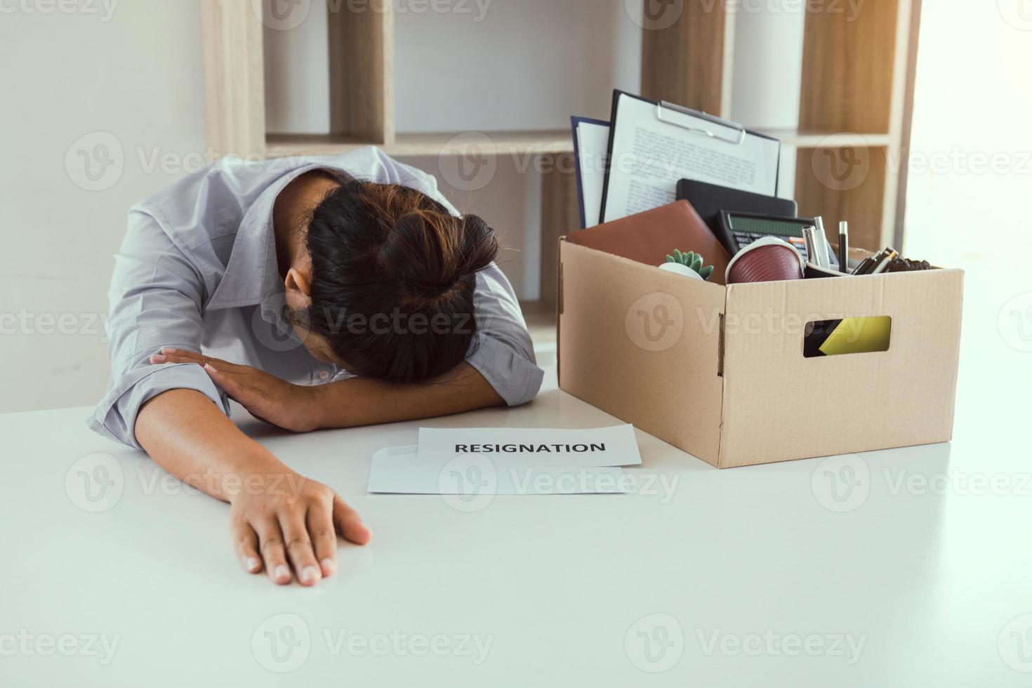 traurige Mitarbeiterin an seinem Schreibtisch, als er den Vertragsumschlag für die Kündigung aus dem Unternehmen erhielt. foto