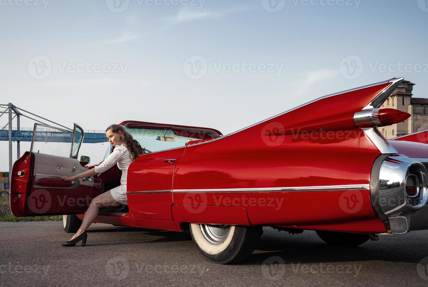 60er Jahre Oldtimer roter Cadillac und ein wunderschönes junges Mädchen foto