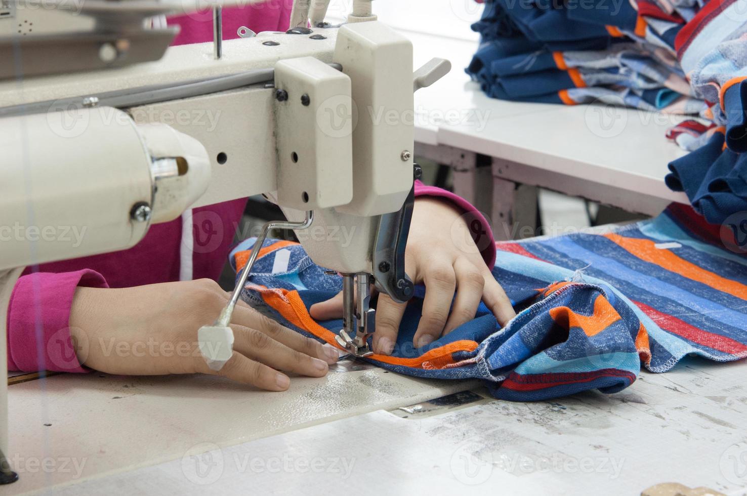 Näherin an der Maschine näht Kleidung in einer Textilfabrik foto