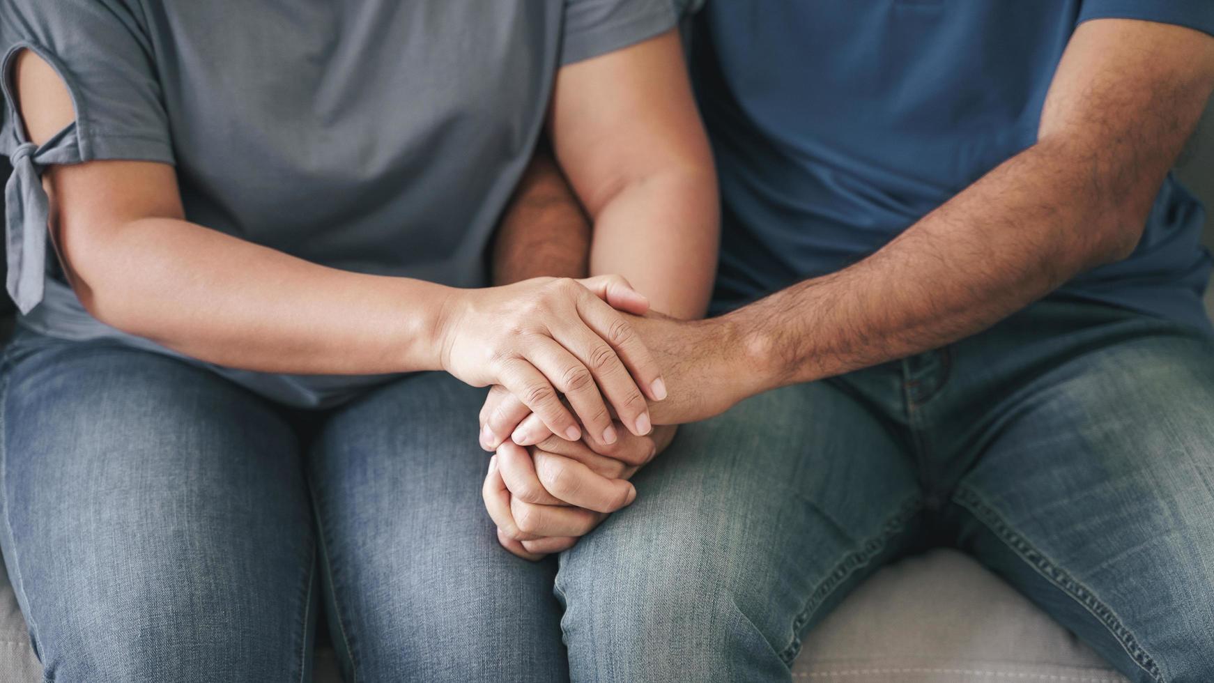 Nahaufnahme eines asiatischen, reifen Paares, das auf der Couch sitzt. frau und ehemann halten sich glücklich und fröhlich an der hand. liebes-, sicherheits- und versicherungsfamilienkonzept foto