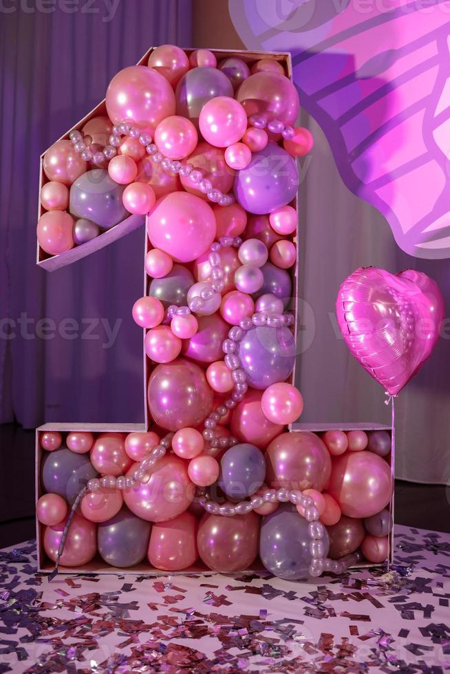 große Nummer eins der rosafarbenen Luftballons zum Kindergeburtstag. ein helles, rosa und violettes Interieur, dekoriert für den ersten Geburtstag des Mädchens. Geburtstagsparty. foto