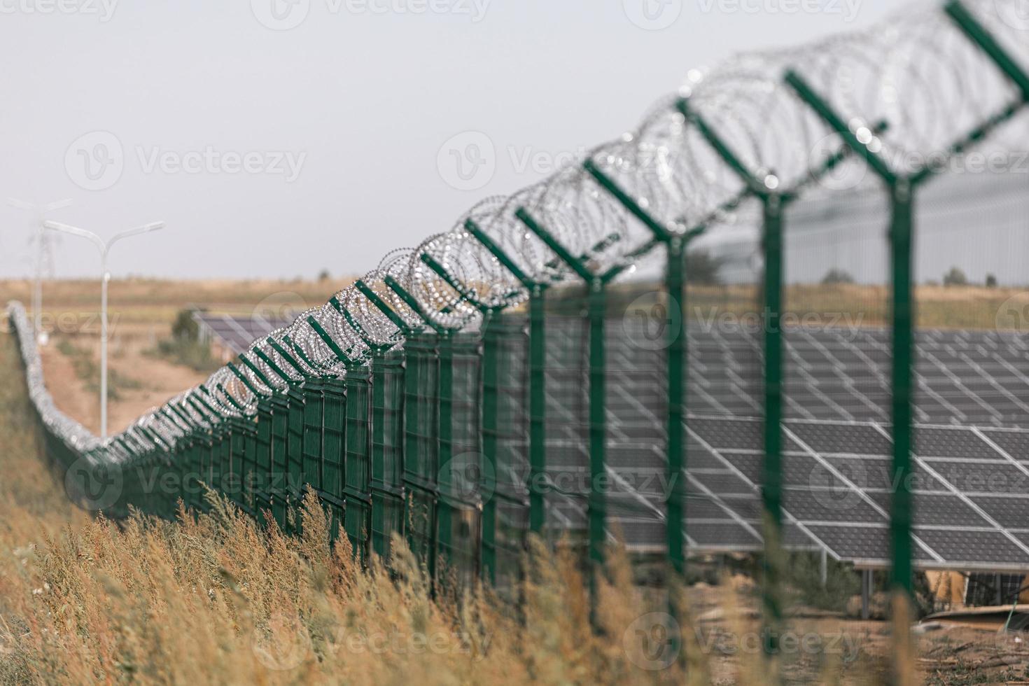 Solarkraftwerk durch Stacheldrahtzaun von der Straße geschützt. Einzäunung sensibler Standorte mit Stacheldraht. foto