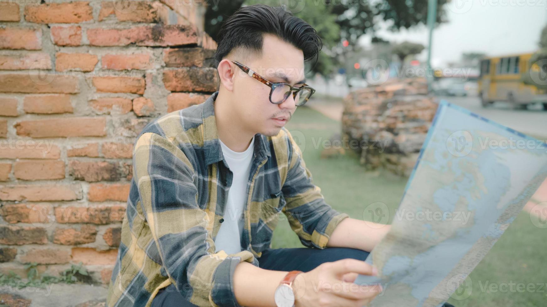 reisender asiatischer mann richtung und blick auf ortskarte während der urlaubsreise in ayutthaya, thailand, rucksacktourist genießen reise in traditioneller stadt. Lifestyle-Männer reisen Konzept. foto