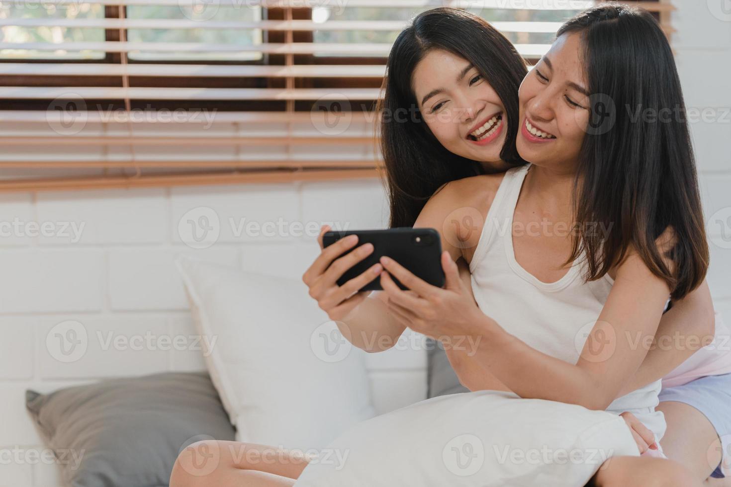 asiatische einflussreiche lesbische lgbtq frauen paar vlog zu hause. junges asiatisches liebhabermädchen, das sich glücklich entspannt, nimmt vlog-video in soziale medien auf, nachdem es morgens im schlafzimmer zu hause auf dem bett liegt. foto