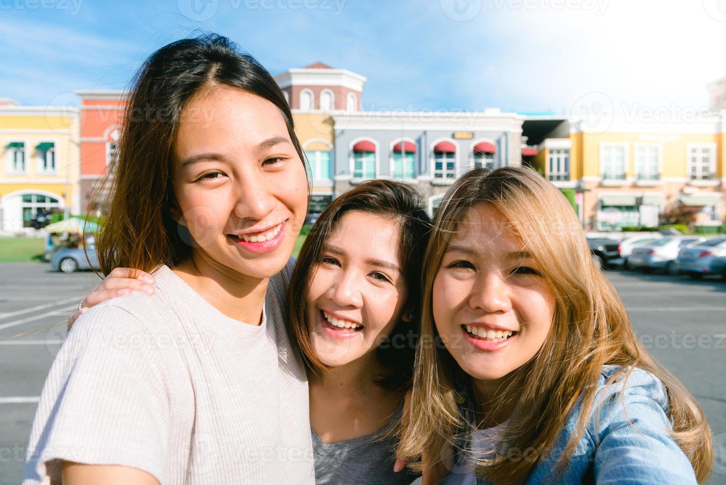 Attraktive schöne asiatische Frau, die beim Einkaufen in der Stadt ein Smartphone benutzt. glückliche junge asiatische Teenagerin in der Stadt, während sie mit ihren Freunden zusammen mit einem Smartphone Selbstporträts macht. foto