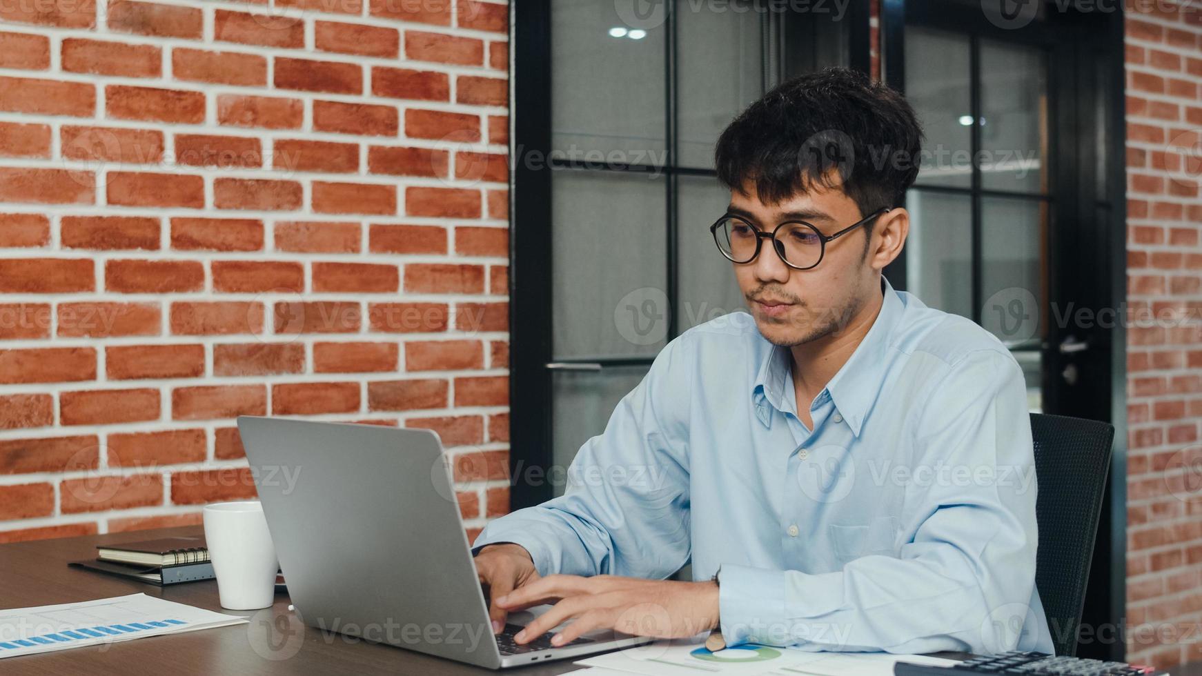 asiatischer kreativer mann, der arbeitsplan auf karton zeichnet. junger professioneller geschäftsmann denken und schreiben informationserinnerung auf papier auf ziegelstein, geschäftssituation, start im loft-bürokonzept. foto