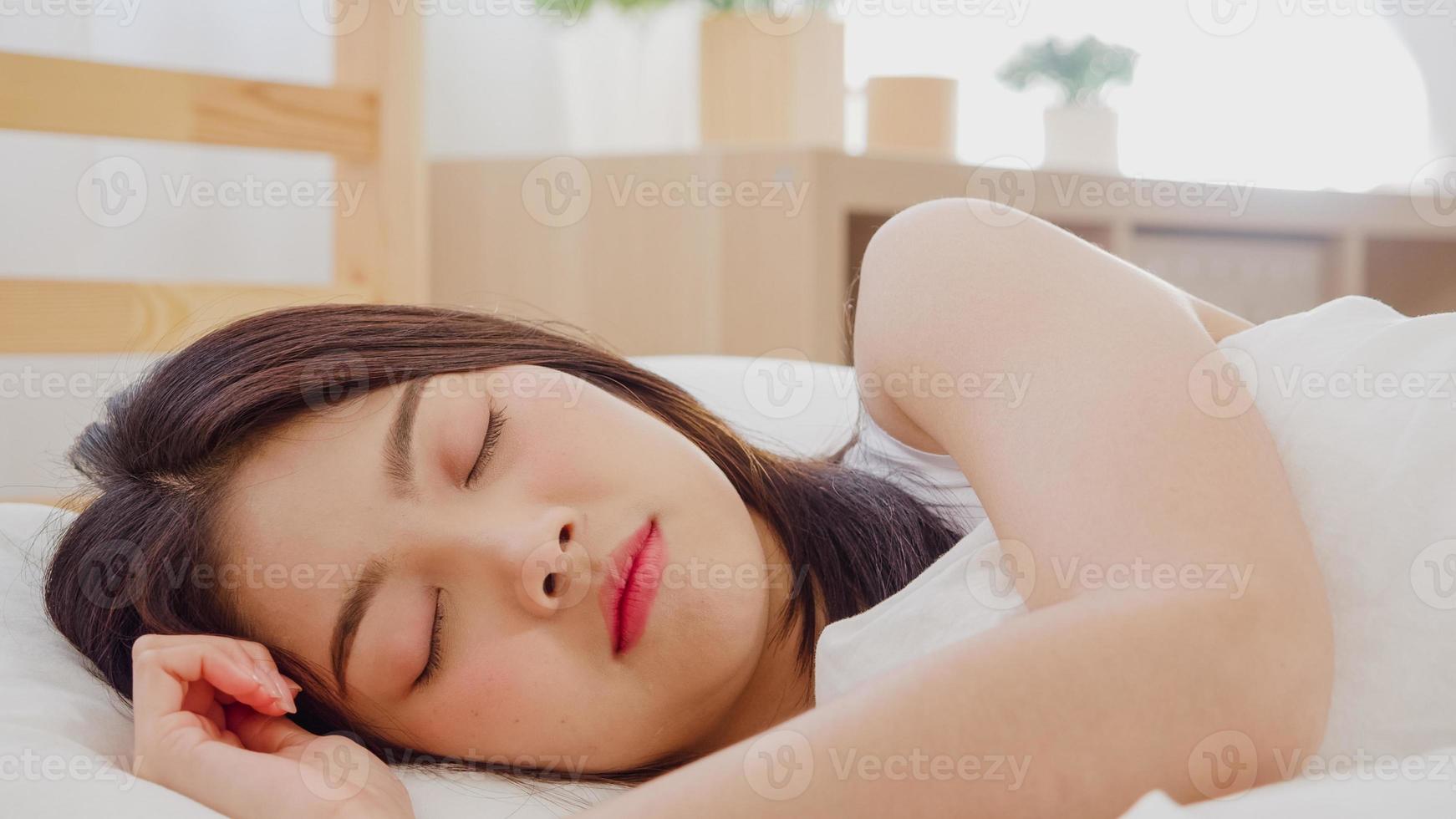 asiatische frau, die träumt, während sie auf dem bett im schlafzimmer schläft, schöne japanische frau, die relaxzeit verwendet, die zu hause auf dem bett liegt. Lifestyle-Frauen mit Entspannungszeit zu Hause Konzept. foto