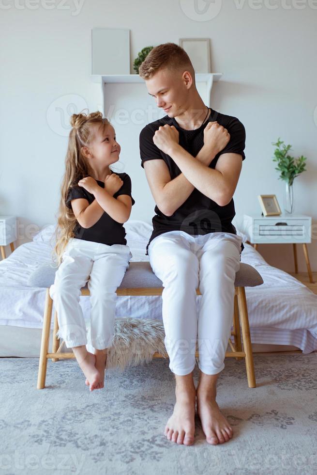 kaukasische geschwister - jugendlicherjungenbruder und kleine mädchenschwester im modernen loftinnenraum des schlafzimmers. typisches Familienleben foto