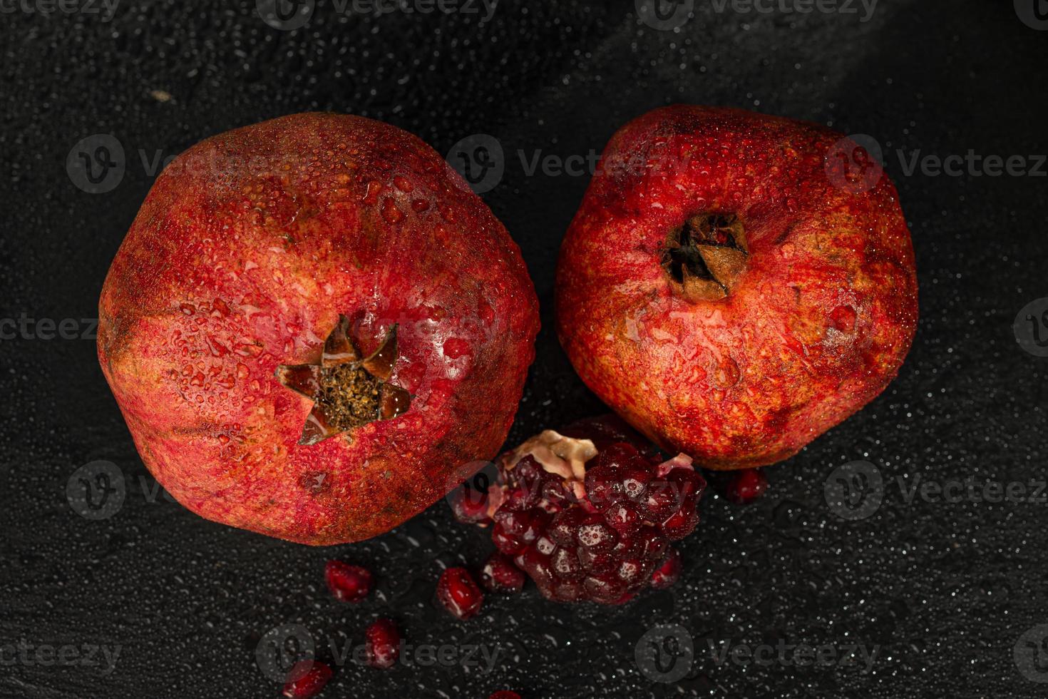 roter reifer nasser Granatapfel auf einem schwarzen Steinbrett foto