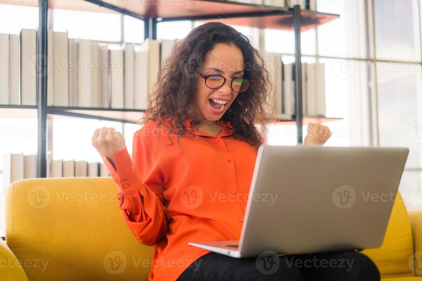 lateinische frau, die mit laptop auf sofa mit glücklichem gefühl arbeitet foto