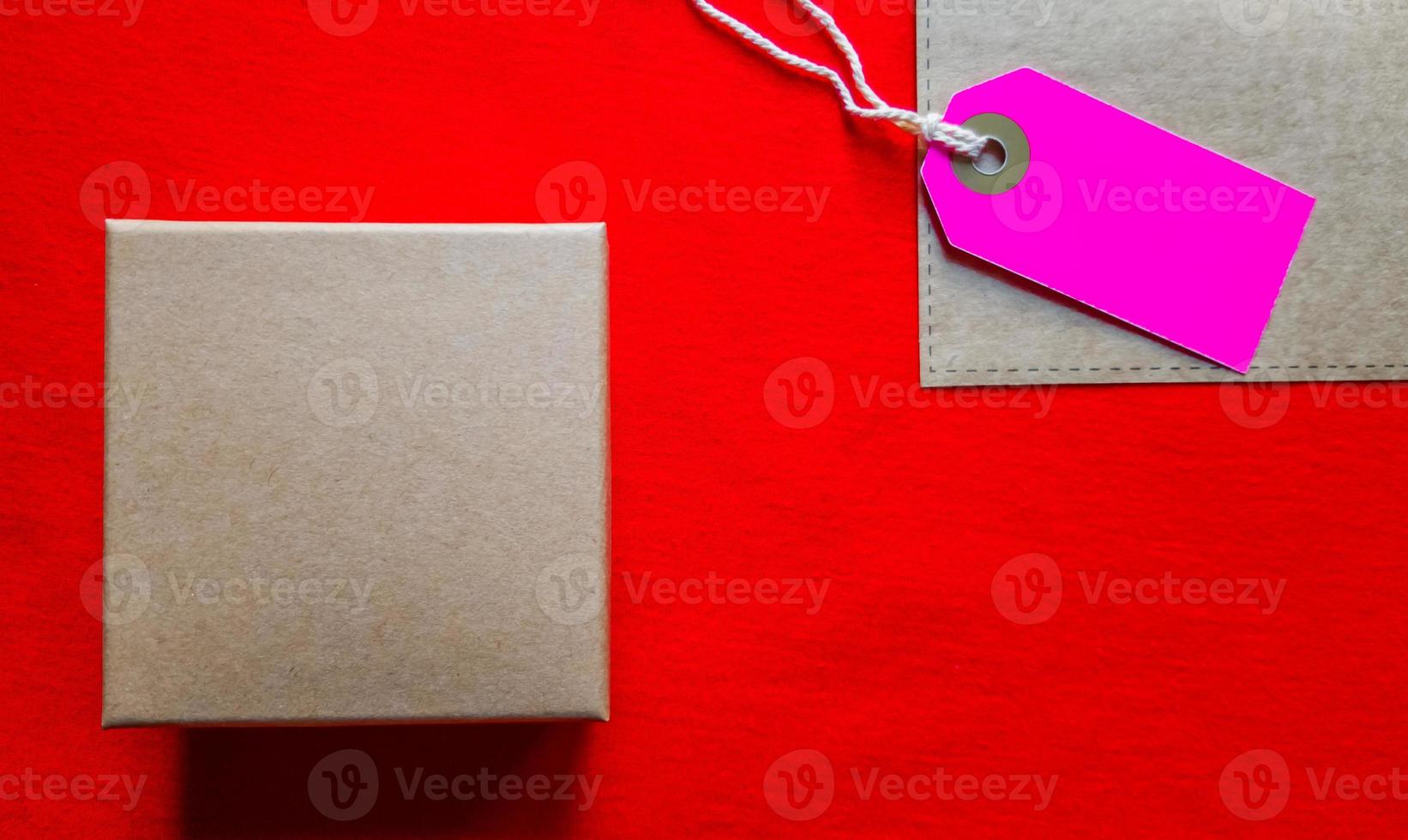 Kartons mit einem Etikett. braune verpackungsbox mit leerem etikett und kopierraum auf rotem hintergrund foto