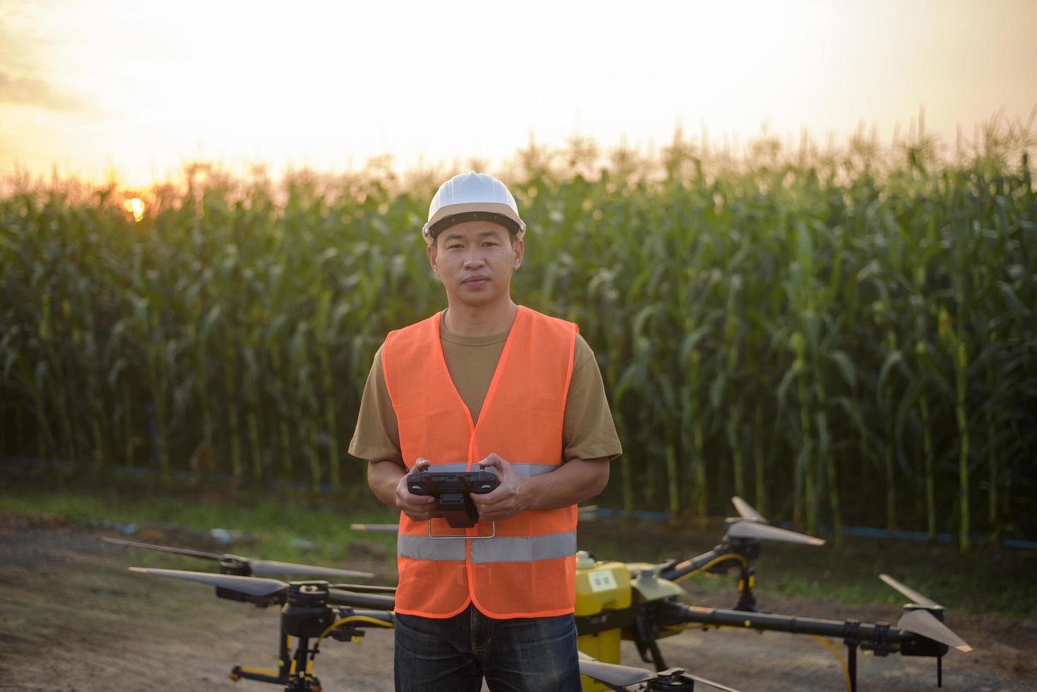 Männlicher Ingenieur, der Drohnen kontrolliert, die Düngemittel und Pestizide über Ackerland sprühen, High-Tech-Innovationen und intelligente Landwirtschaft foto