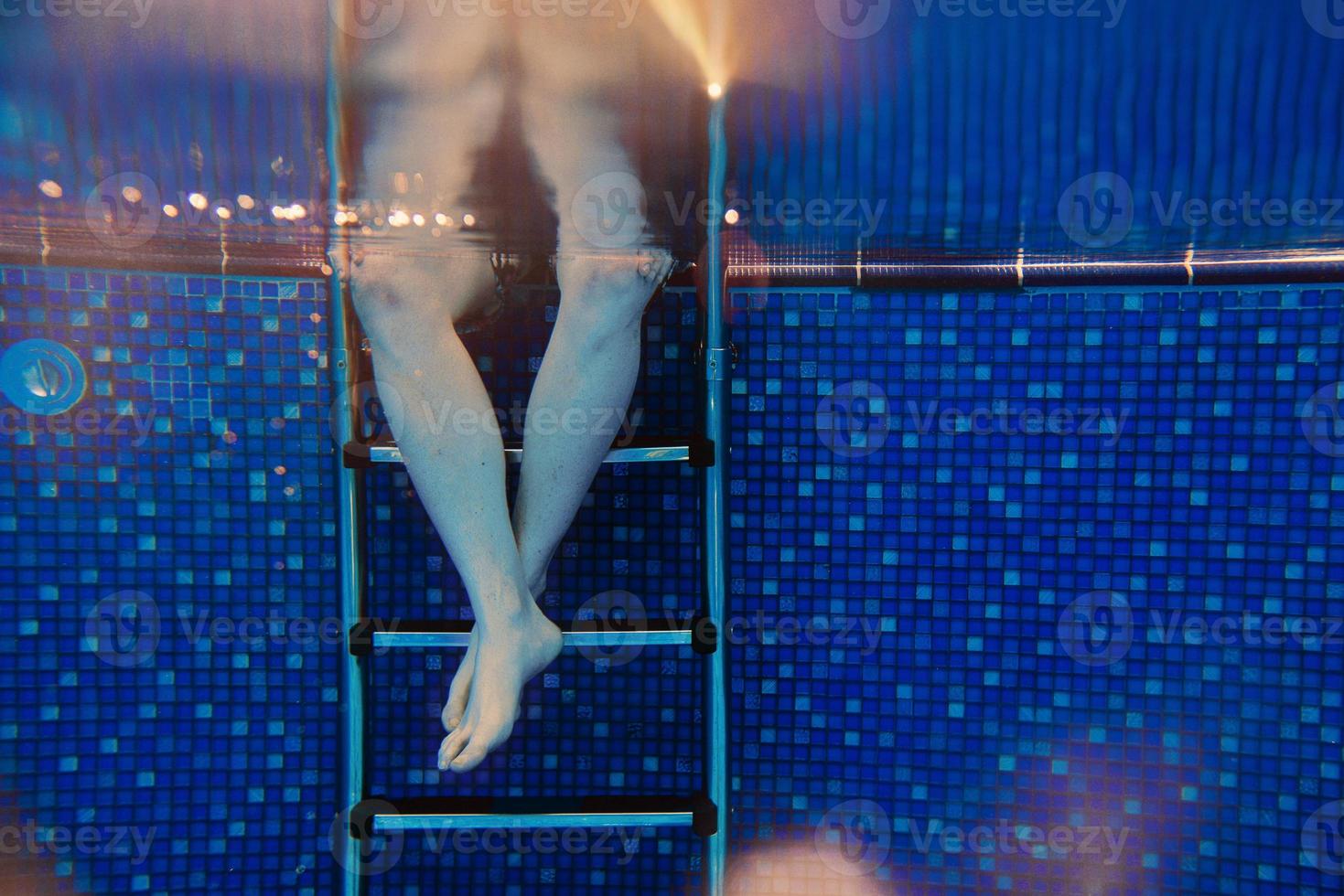 Männerbeine auf der Treppe unter Wasser im Schwimmbad im Sommer foto