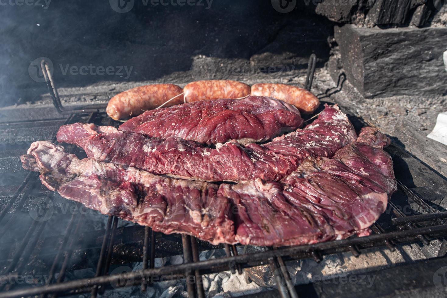 Typisches uruguayisches und argentinisches Asado, das auf Feuer zubereitet wird. Entrana- und Vacio-Fleischstücke. begleitet von Chorizo. foto