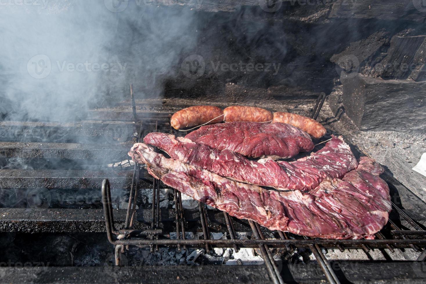 Typisches uruguayisches und argentinisches Asado, das auf Feuer zubereitet wird. Entrana- und Vacio-Fleischstücke. begleitet von Chorizo. foto
