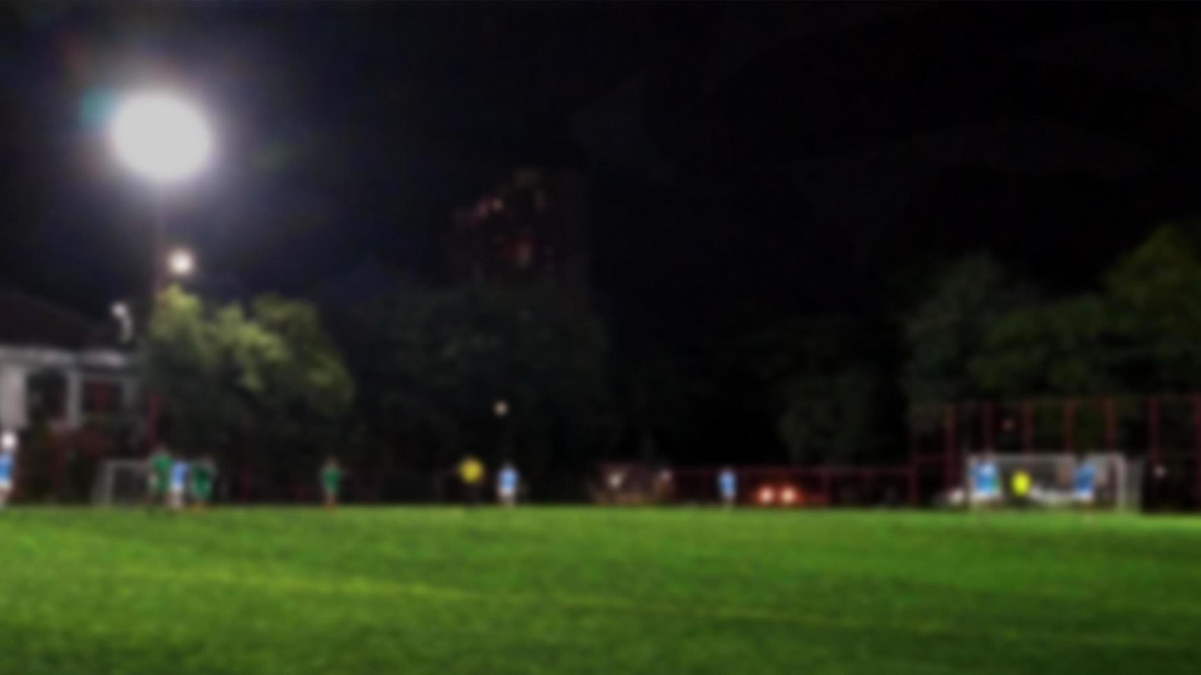 Defokussierter Landschaftsfußballplatz bei Nacht mit Beleuchtung. textraum kopieren. foto