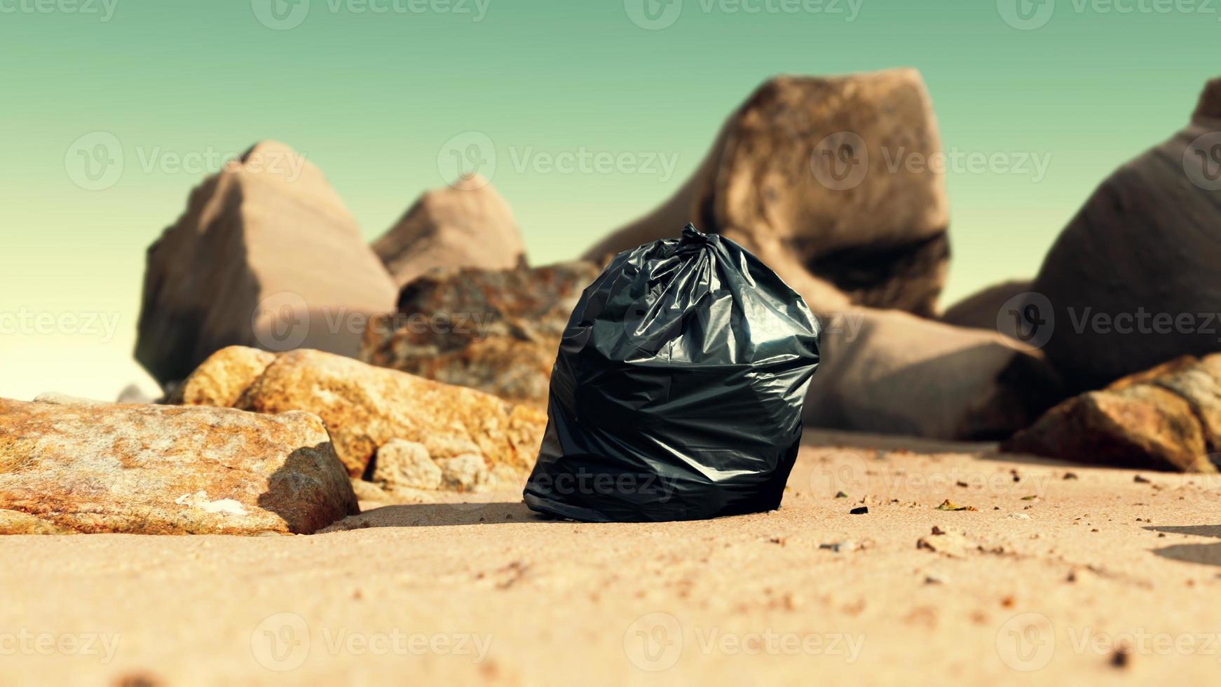 Schwarze Mülltüte aus Plastik voller Müll am Strand foto