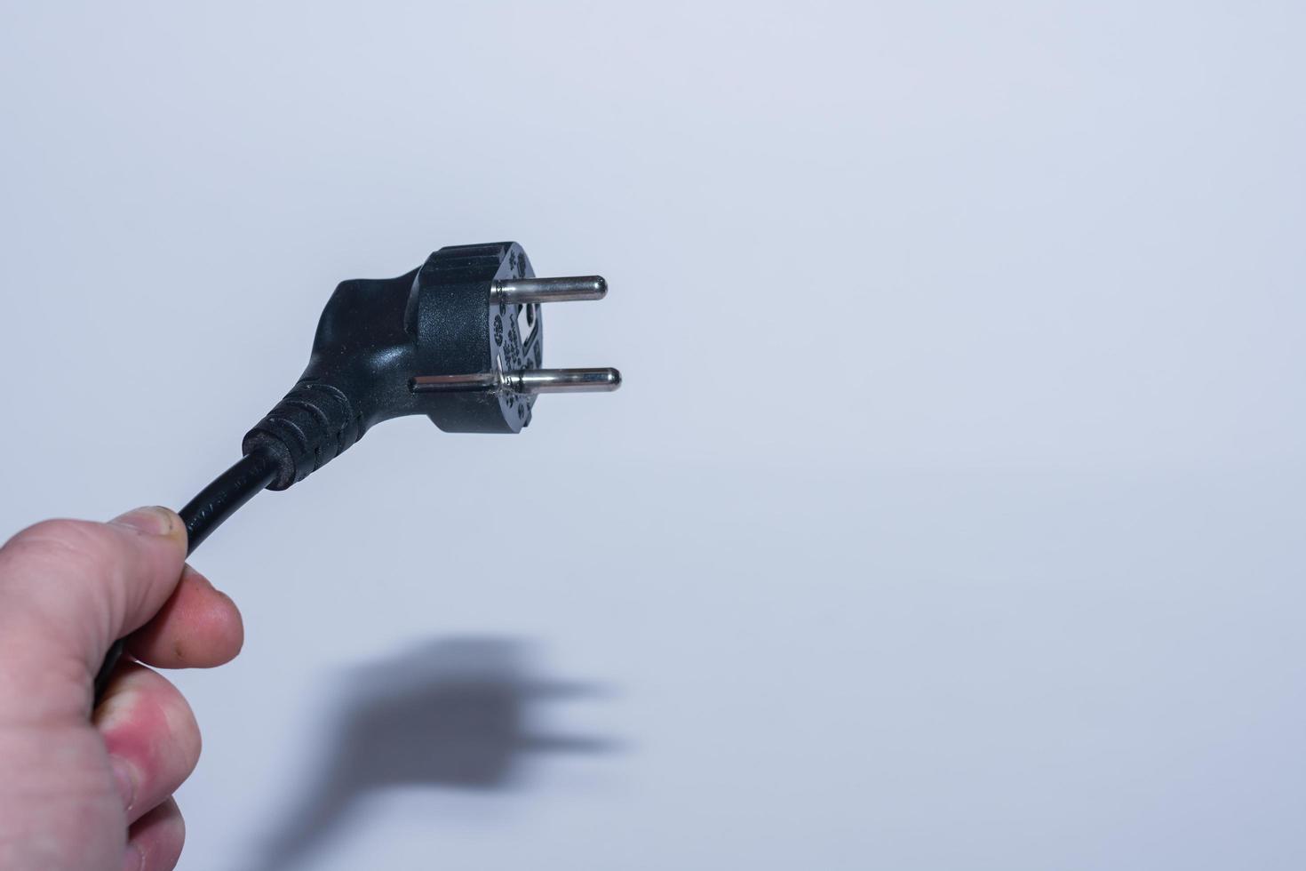 stecker aus strom schräg in einer hand gehalten strom sparen linke ansicht mit grau foto