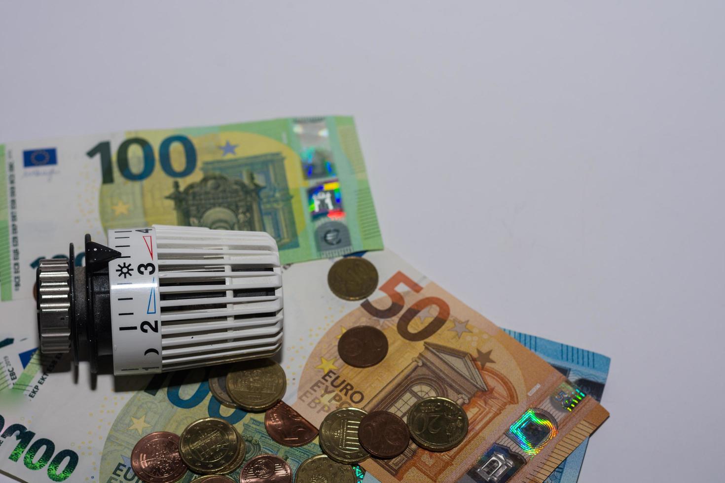 energiepreise steigen und energieverbrauch thermostatregler von heizung mit verschiedenen euro-scheinen und münzen linke seite foto