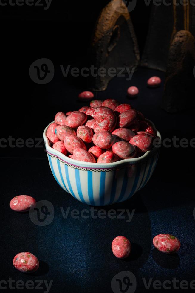 Schoko-Dragees in knusprig farbiger Glasur. Dragee mit Mandeln in einer Vase. bunte Bonbons auf dem Tisch foto