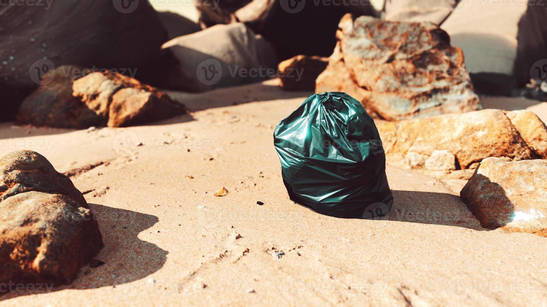 Schwarze Mülltüte aus Plastik voller Müll am Strand foto