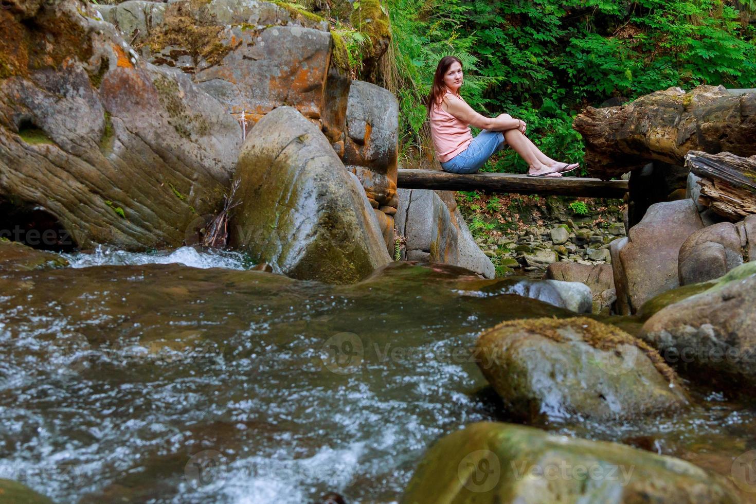 Frau sitzt an der Holzbrücke foto