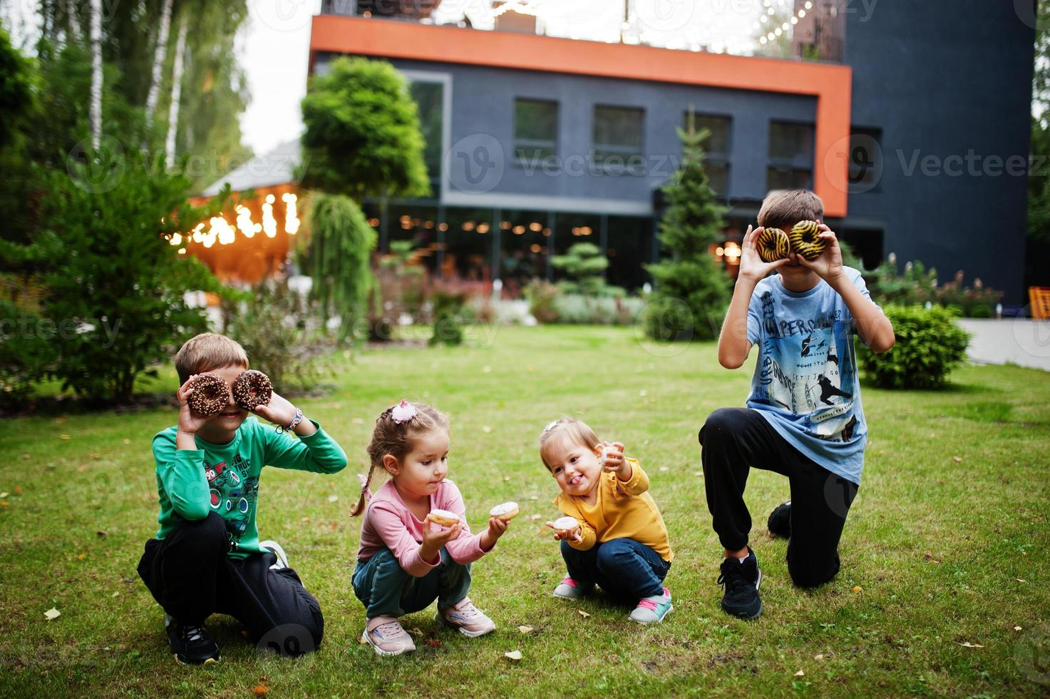 vier kinder mit donuts im abendhof. leckeres leckeres Donut-Essen. foto