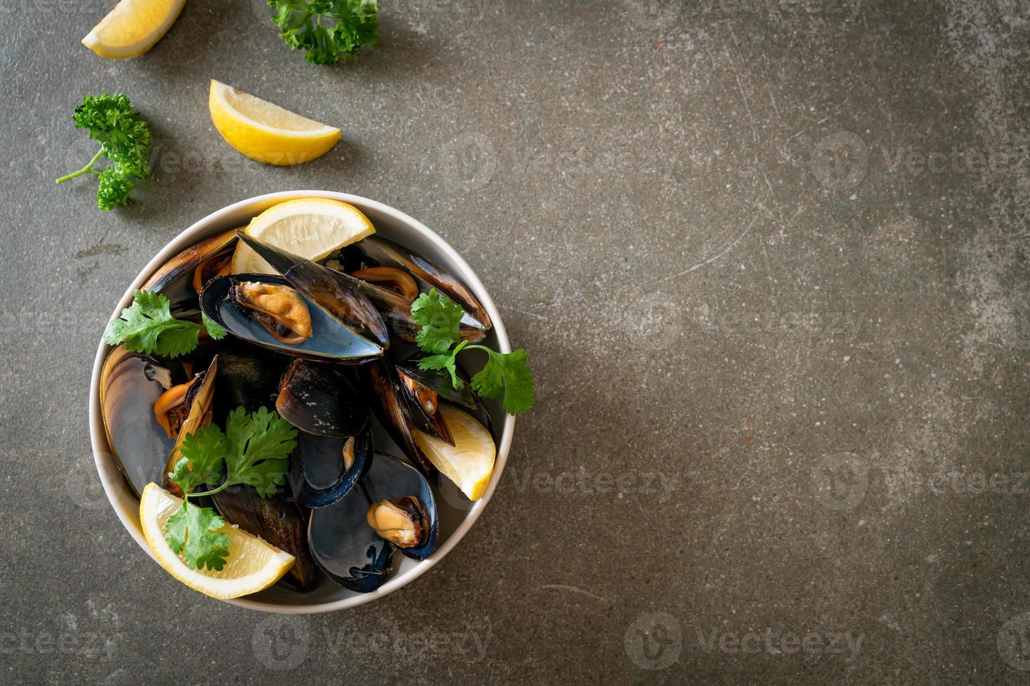 Muscheln mit Kräutern in einer Schüssel mit Zitrone foto