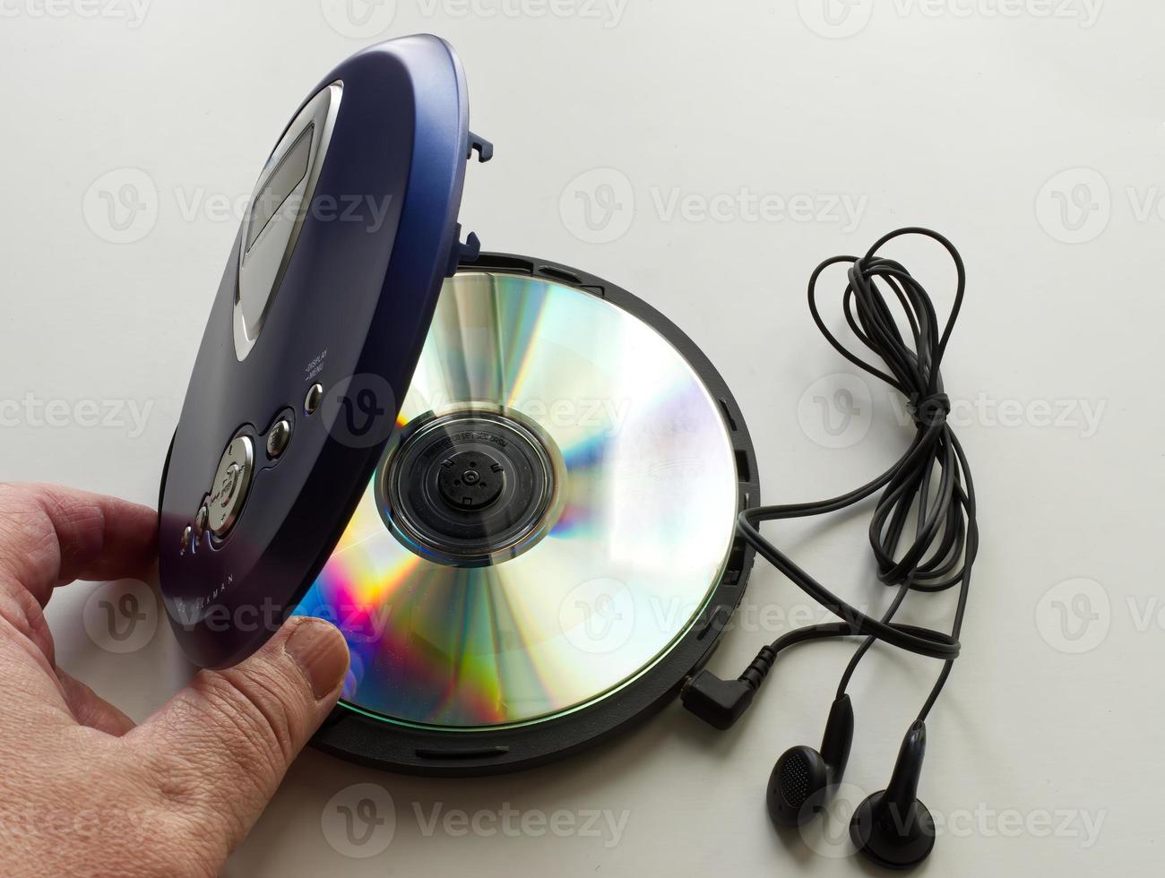 Hand öffnet einen alten CD-Walkman mit Kopfhörern auf weißem Hintergrund. Vintage-Technologie aus den 90er Jahren. foto