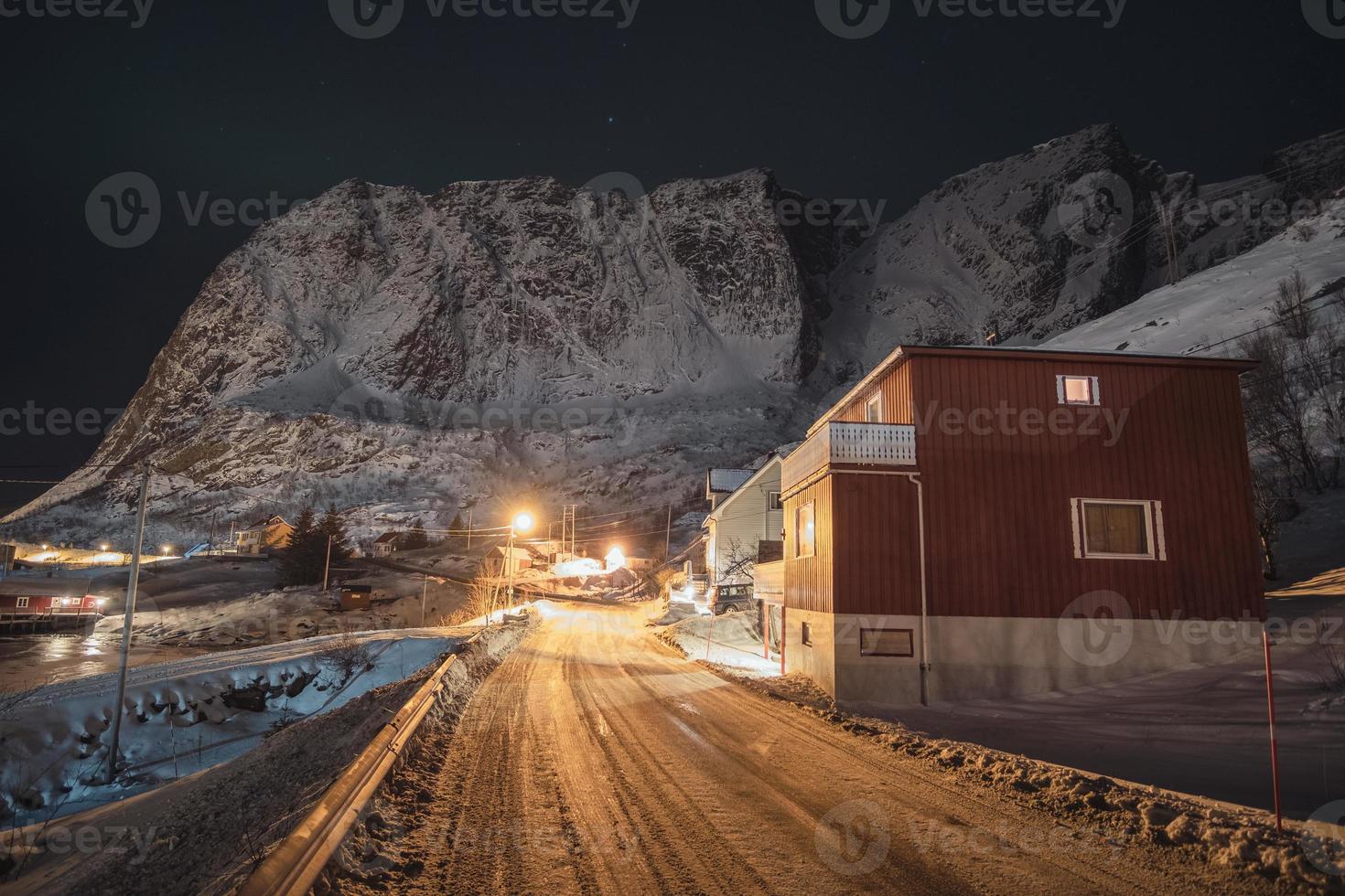 norwegisches Dorf auf Landstraße mit hell leuchtenden und schneebedeckten Bergen foto