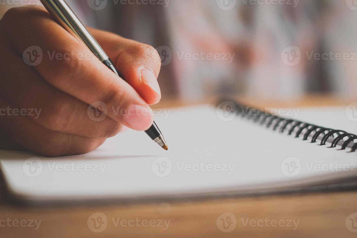 Mannhand mit Stiftschreiben auf Notizbuch. foto