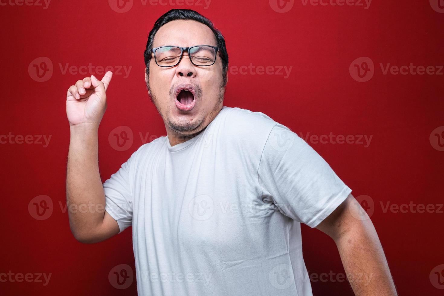 junger gutaussehender mann mit bart, weißem t-shirt und brille, der glücklich und fröhlich tanzt, lächelt, sich lässig bewegt und selbstbewusst musik hört foto