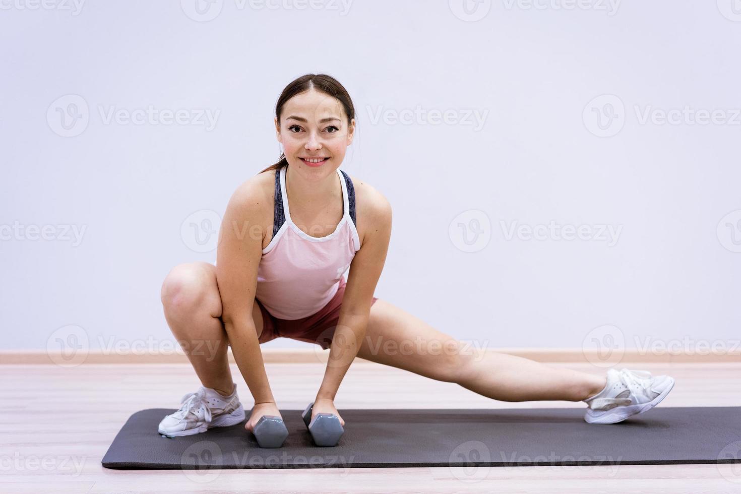 glückliche frau, die zu hause yoga vor wandhintergrund macht foto