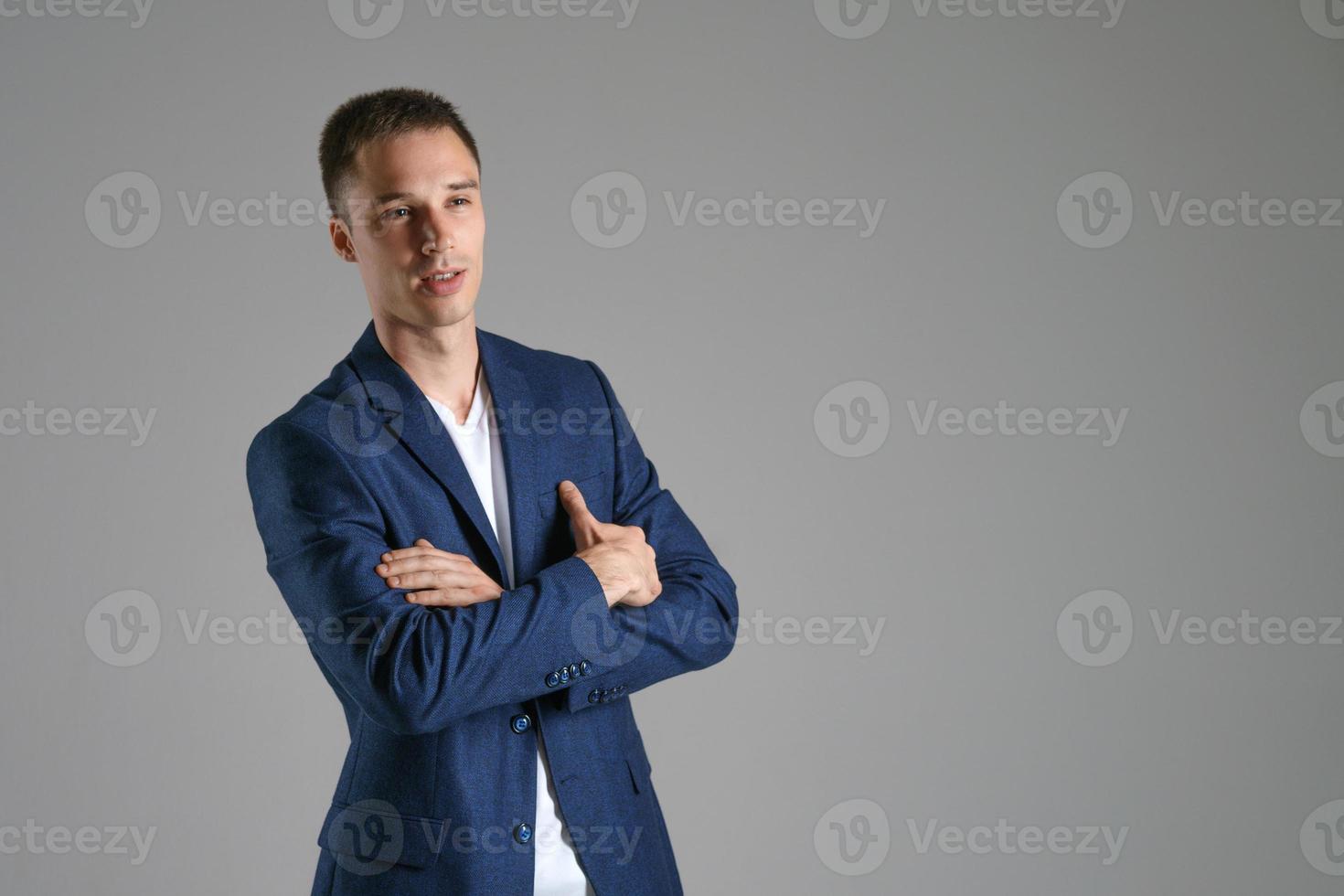 Ein junger Geschäftsmann in einer blauen Jacke auf grauem Hintergrund foto