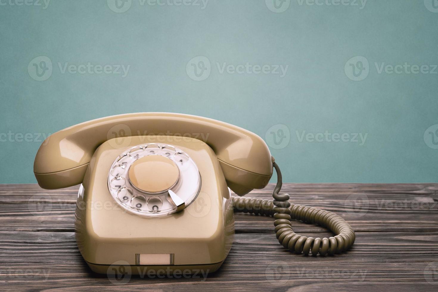 Altes Telefon steht auf den Holzbrettern, die auf blauem Hintergrund isoliert sind foto