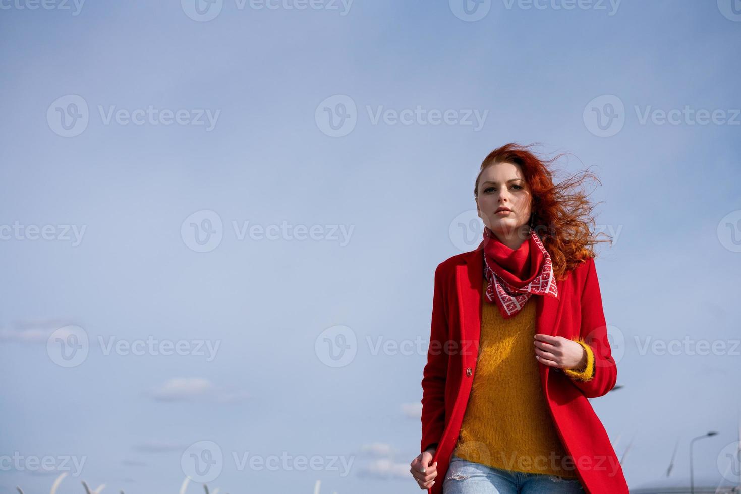 Eine junge Frau läuft im Wind vor dem Hintergrund des Himmels. foto