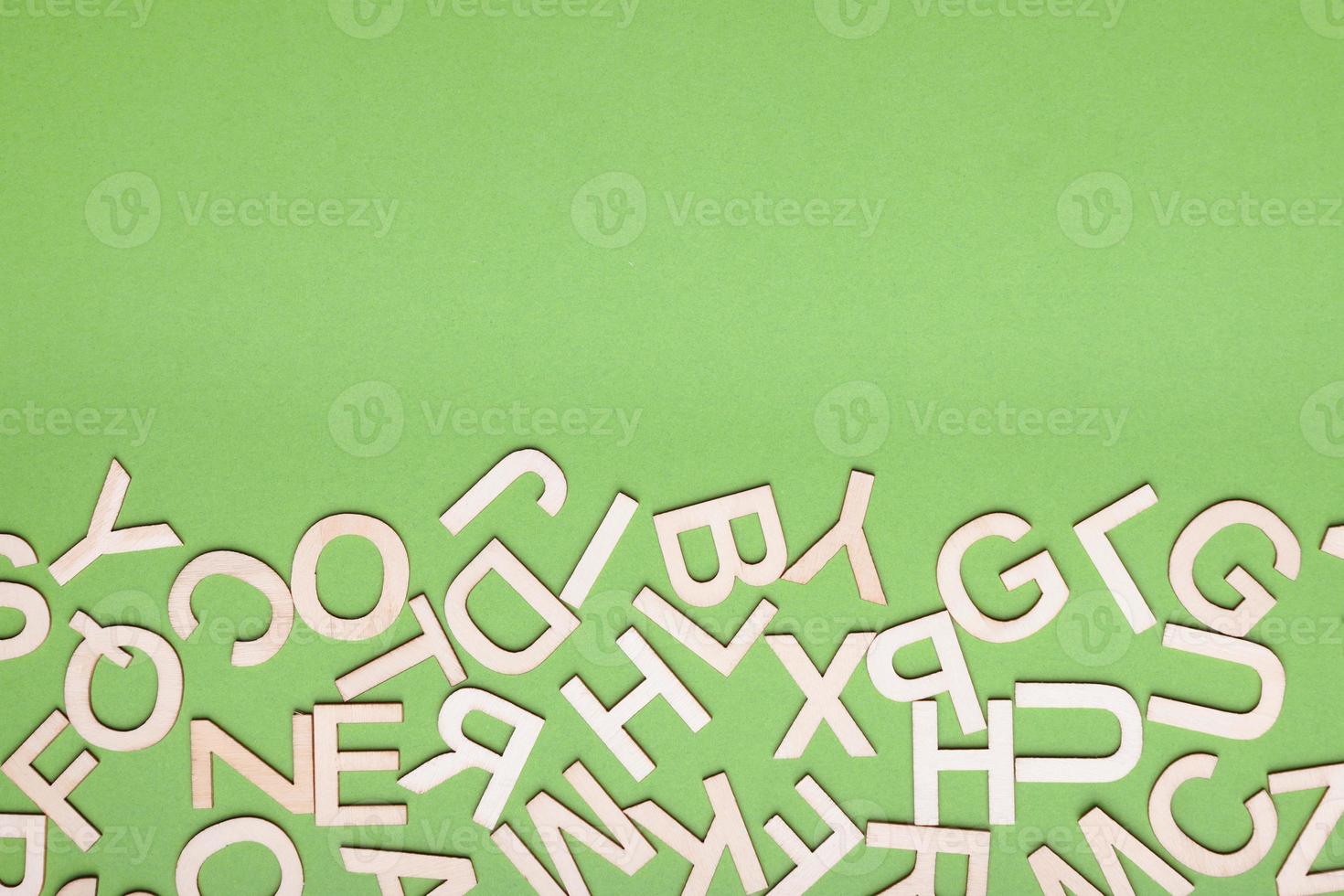 Sammelsurium von Holzbuchstaben auf grünem Papierhintergrund foto