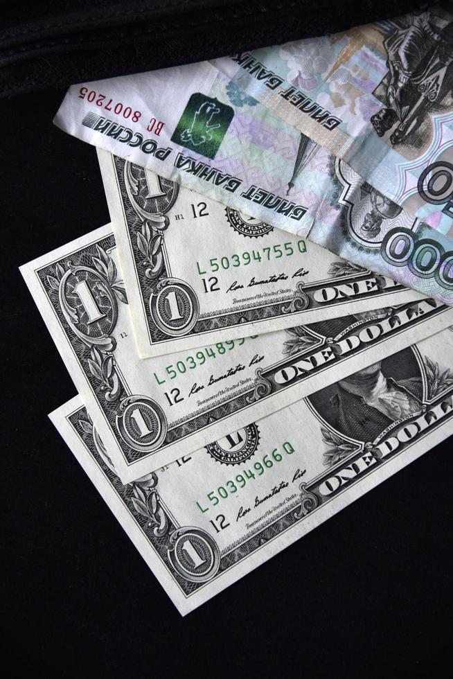 Dollarscheine und Rubel aus einer schwarzen Brieftasche foto
