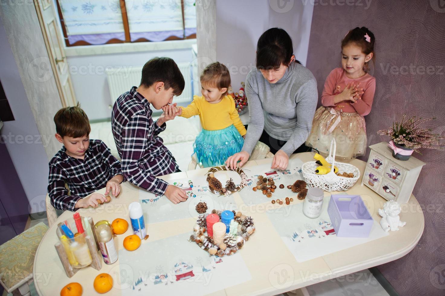 mutter mit vier kindern macht einen kranz für heiligabend und bastelt dekorieren. Neujahr Feierlichkeiten. foto