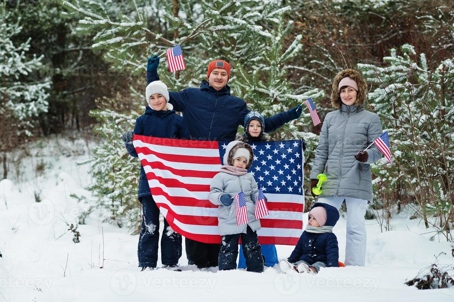 familie mit vier kindern, die flagge von usa auf winterlandschaft halten. foto