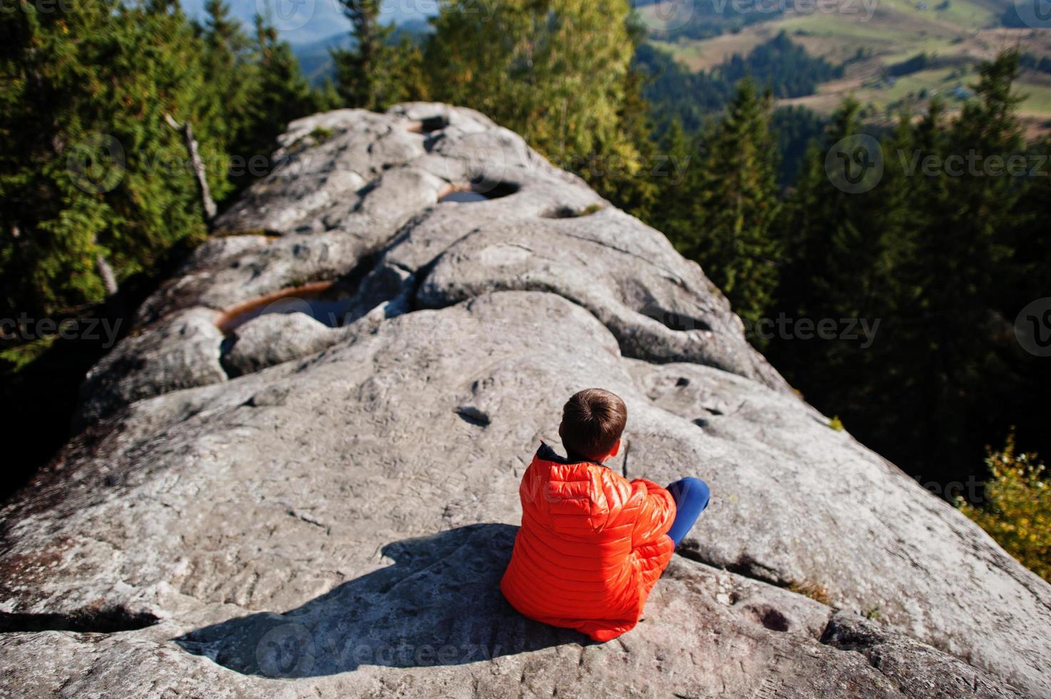 Junge oben auf dem Berg. Kinder wandern an einem schönen Tag in den Bergen, ruhen sich auf Felsen aus und bewundern die atemberaubende Aussicht. aktiver familienurlaub freizeit mit kindern. spaß im freien und gesunde aktivität. foto