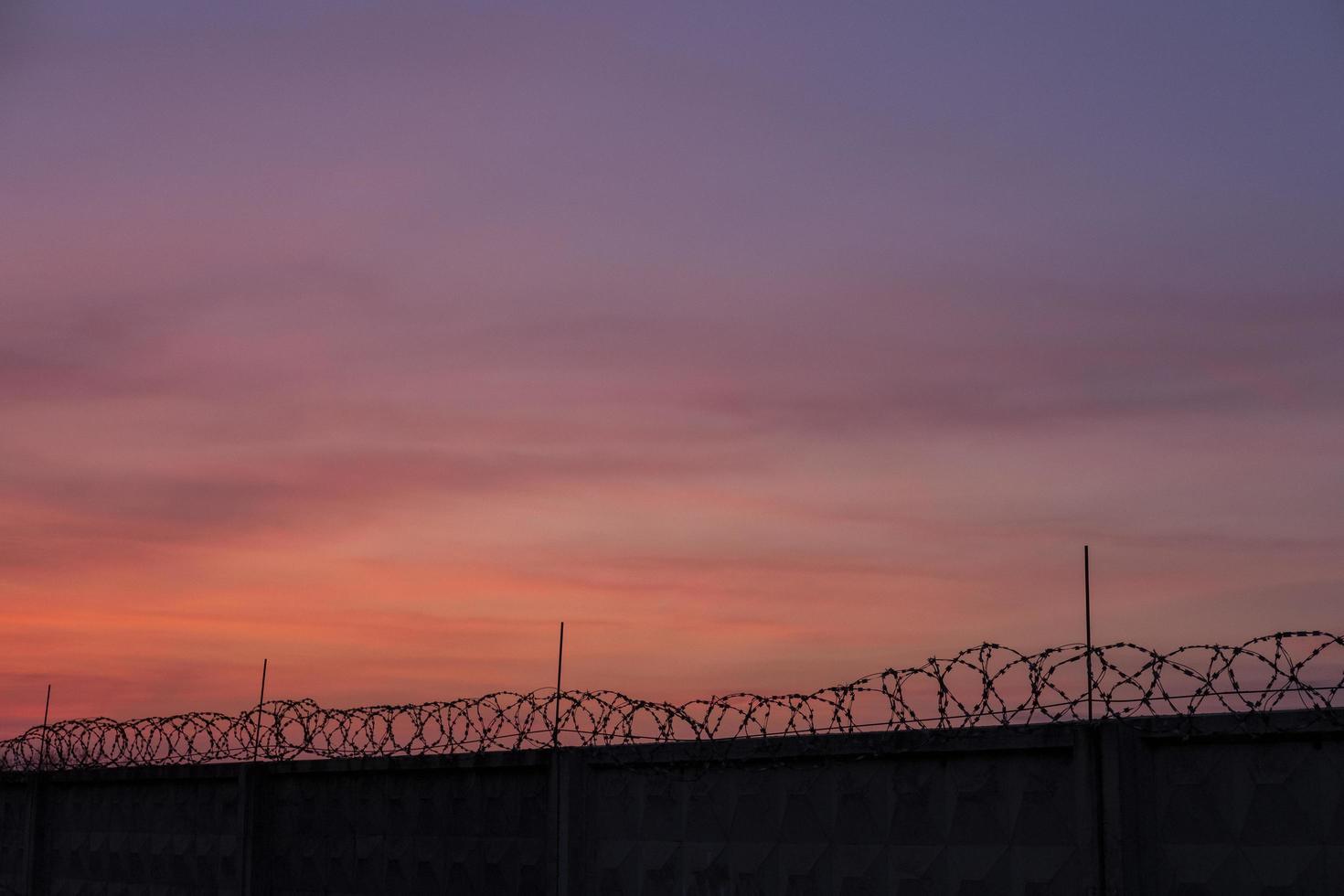 Silhouette von Stacheldraht gegen Sonnenuntergang Himmel foto